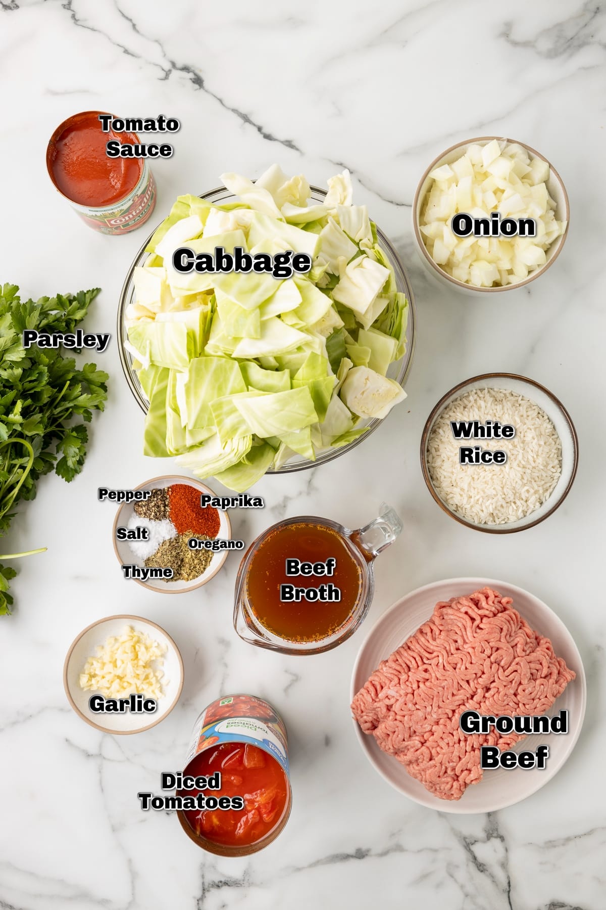unstuffed cabbage rolls ingredients Ingredients for unstuffed cabbage rolls including cabbage, beef, rice, tomatoes, broth, and spices on a marble counter.