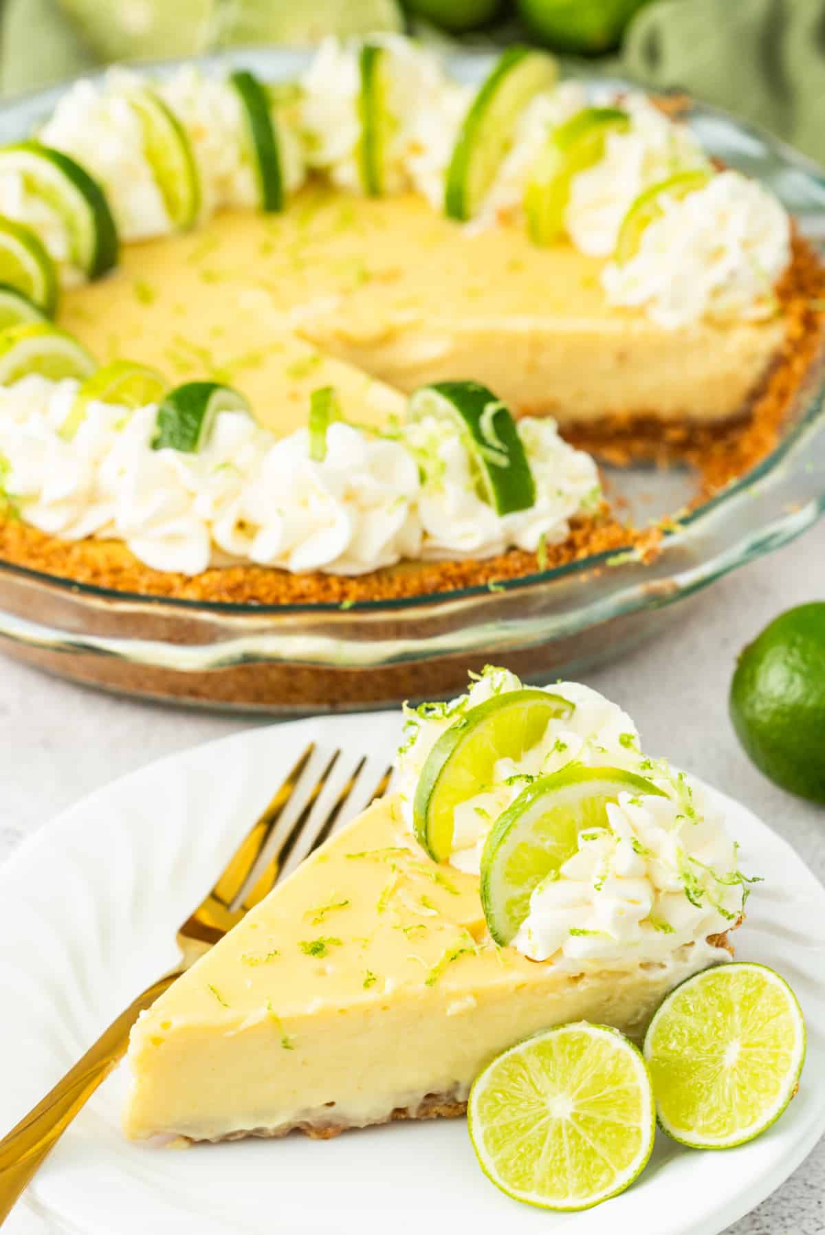 Plated key lime pie with gold fork Slice of key lime pie on a plate with a gold fork beside it