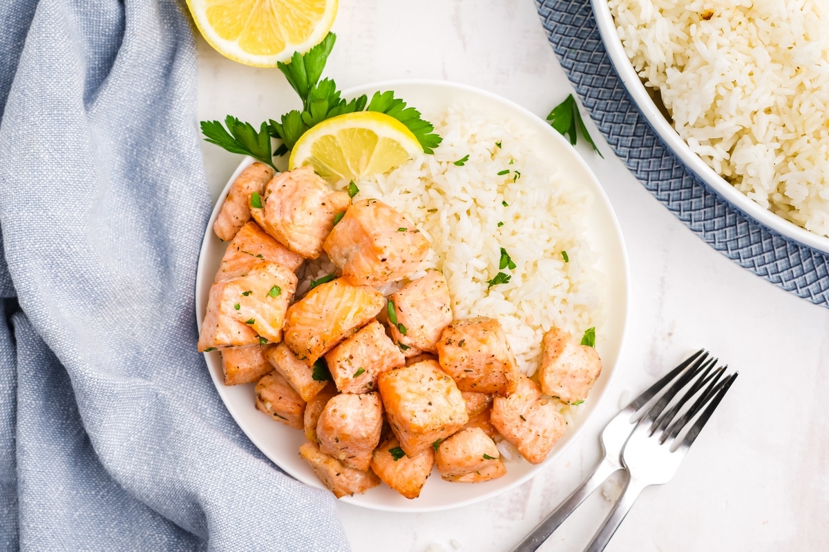 Air Fryer Salmon Bites on a tabletop. salmon bites made in the air fryer served on a plate with rice