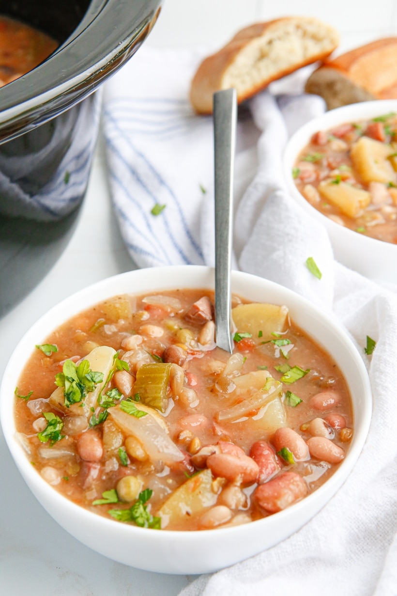 Bowl of finished ham and bean soup with a spoon resting inside, ready to eat.