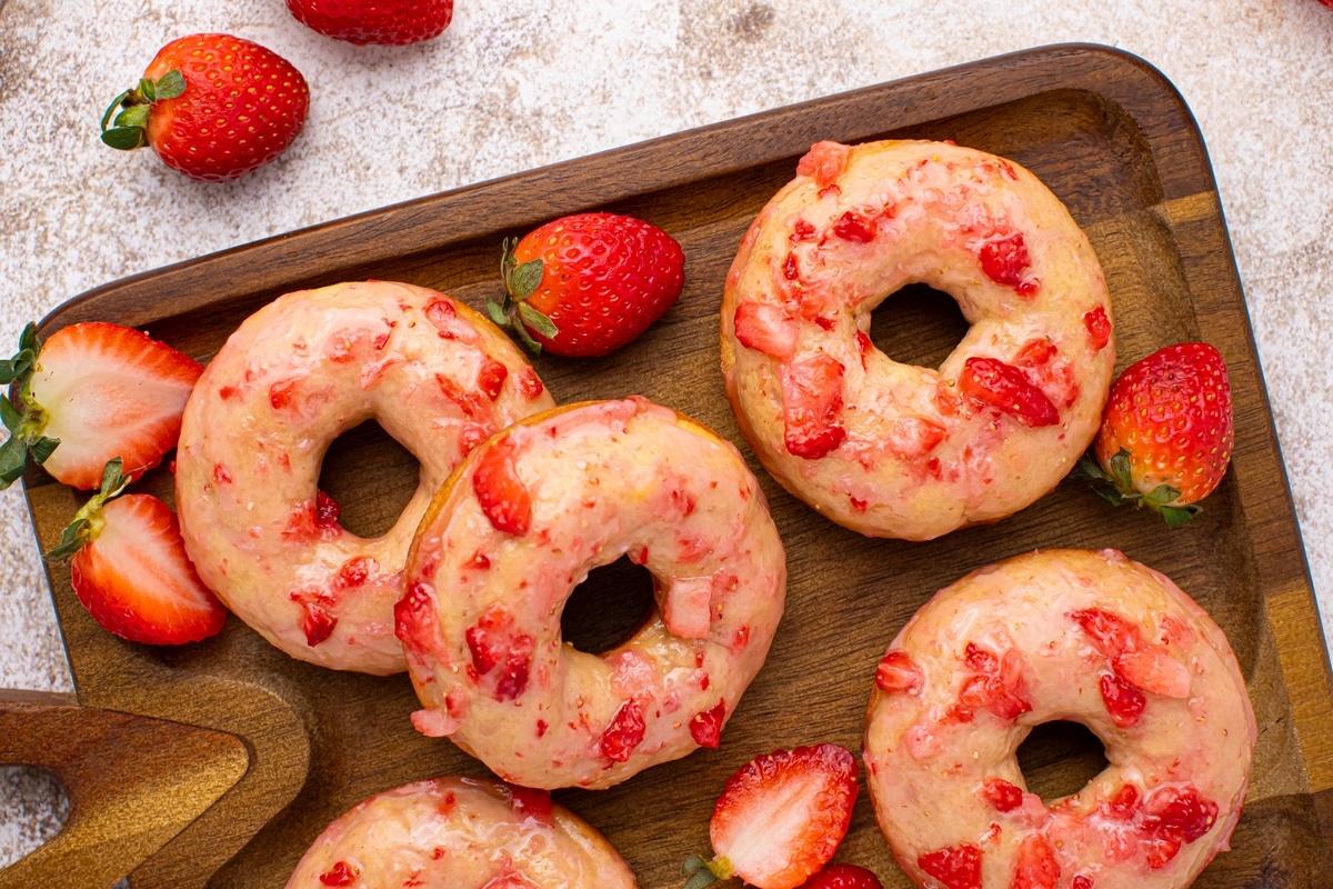 Vanilla Baked Doughnuts with Fresh Strawberry Glaze on a wooden serving tray strawberry glazed baked donuts