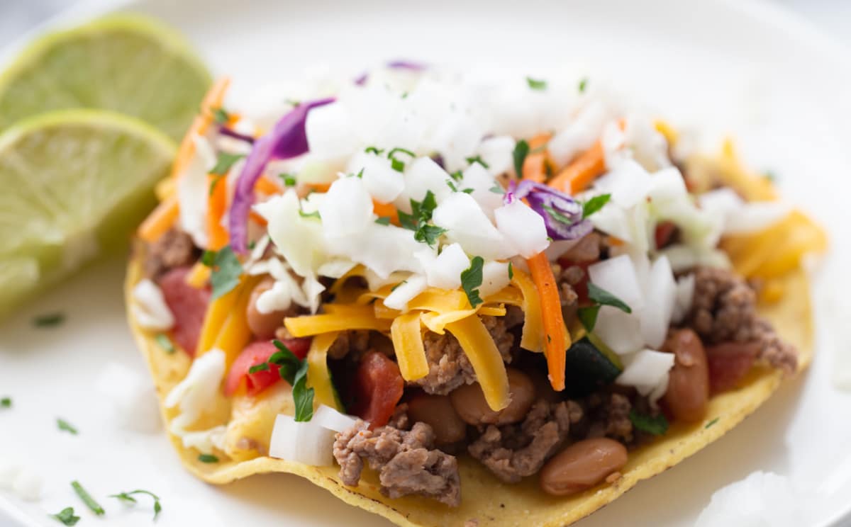 Side View of Chipotle Beef Tostada Side angle of stacked tostada showing beef, cheese, and lime slaw layers