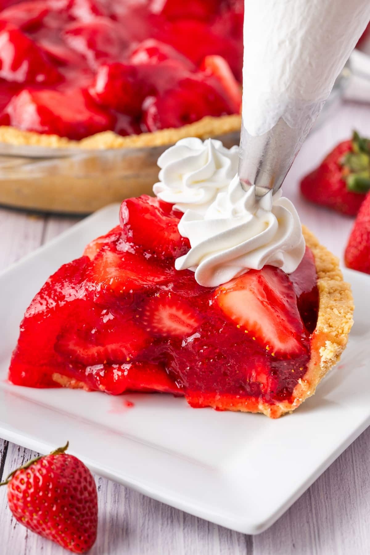 Satisfy your sweet tooth with a delicious fresh strawberry pie. This easy no-bake dessert is perfect for summer. whipped cream on strawberry pie