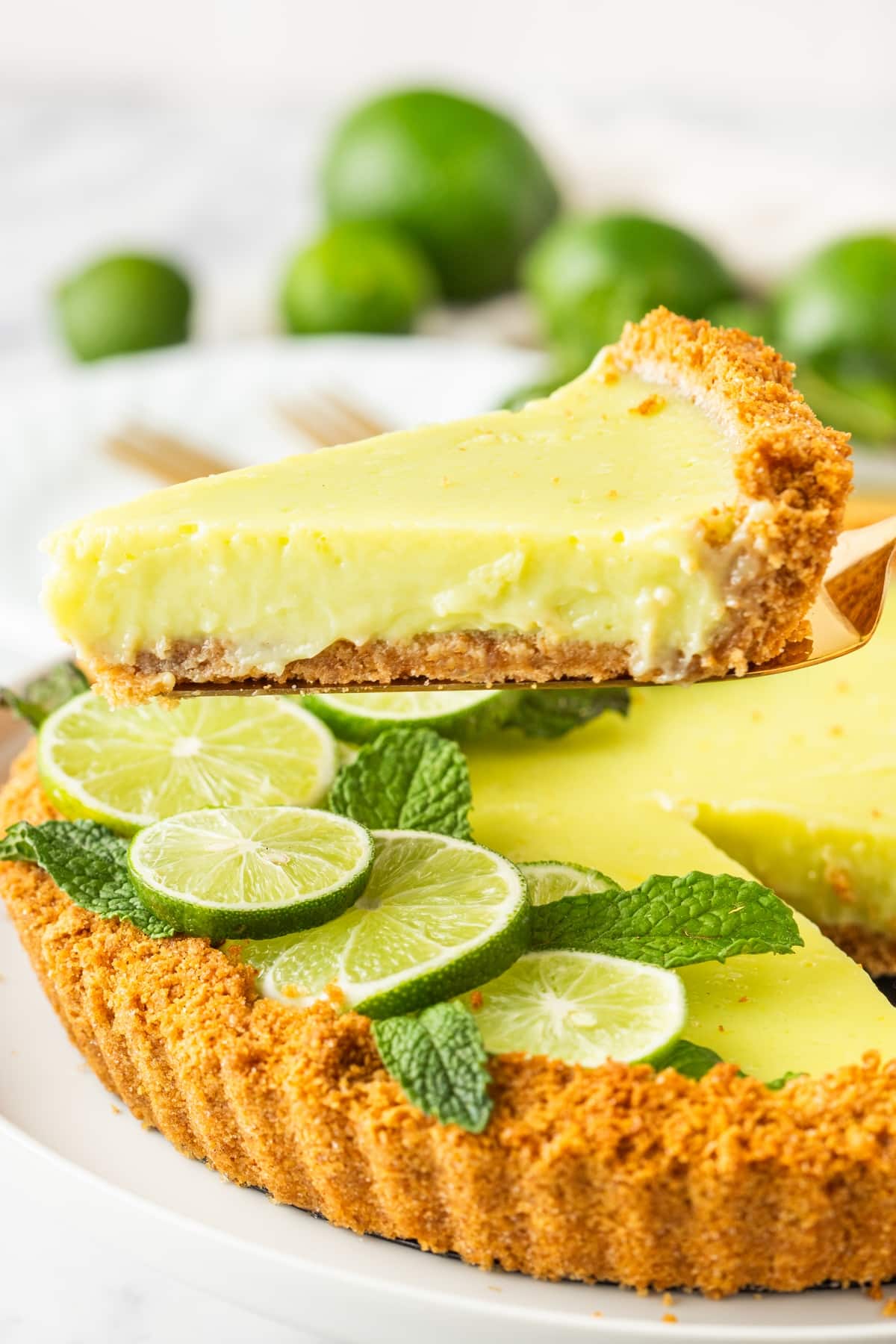 A slice of Key lime tart being lifted from the pan with crust and filling in view 