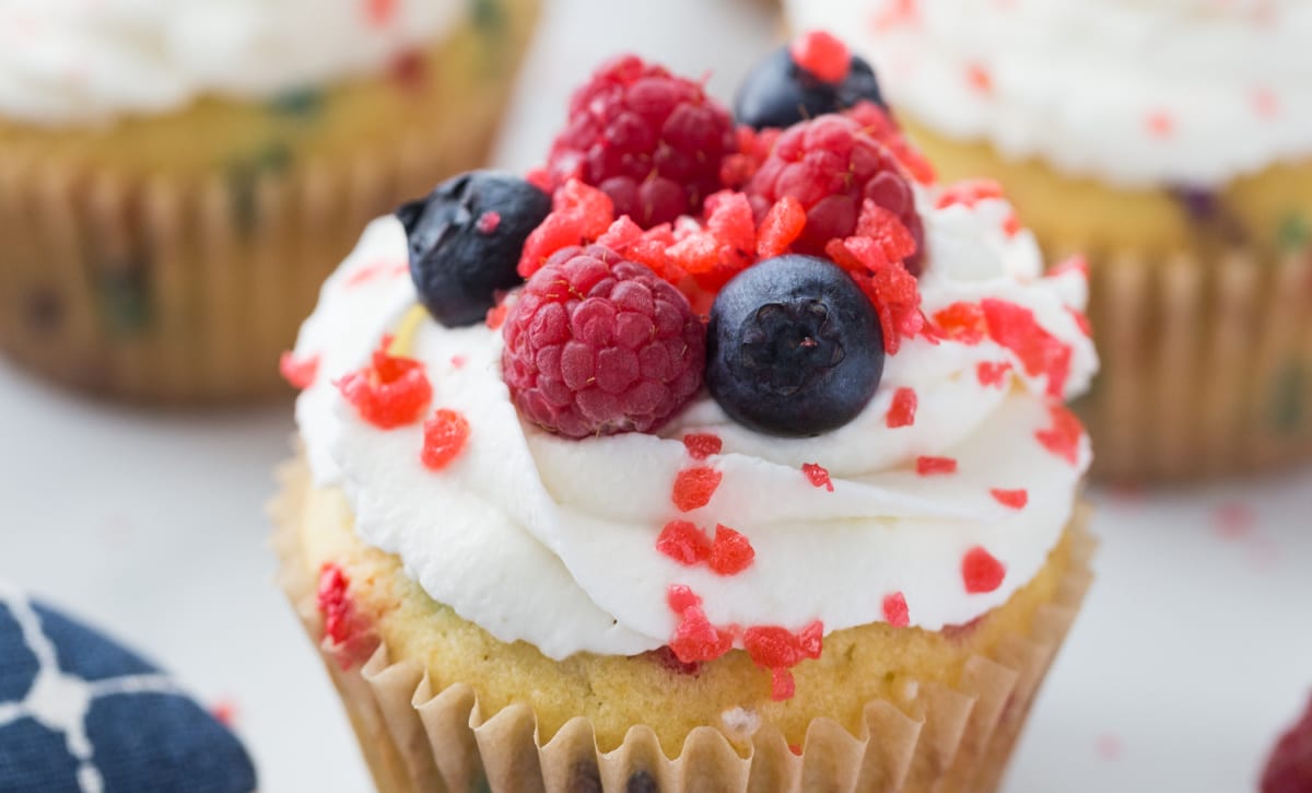 4th of July cupcakes decorated with whipped cream, berries, and popping candy.