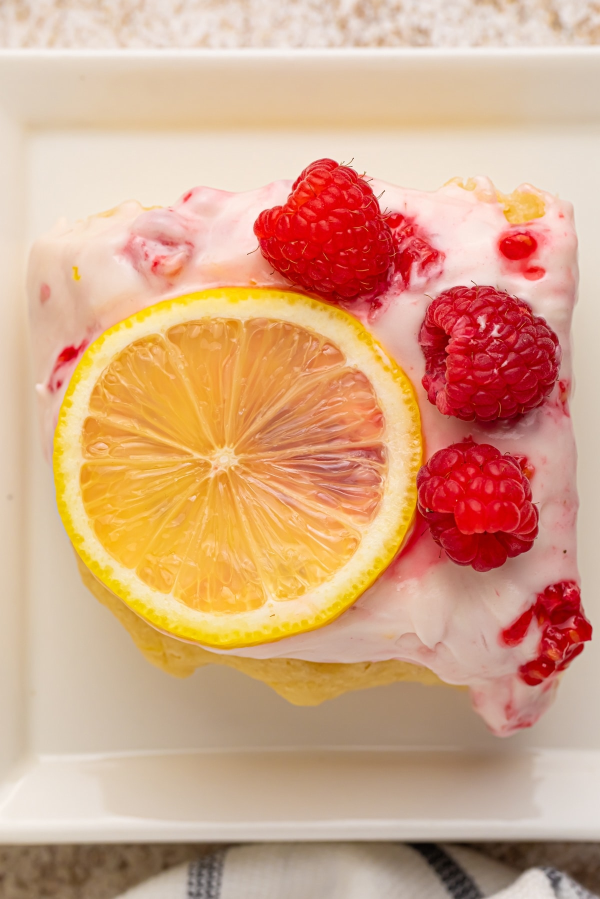A buttermilk lemon raspberry frosted sheet cake made with —sun-ripened raspberries and tart lemon. It's one deliciously tender cake! a slice of raspberry lemon cake