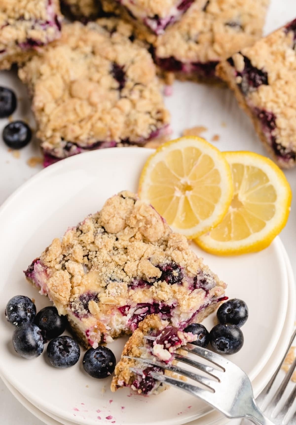 Fork pulling a bite from a sliced lemon blueberry crumble bar