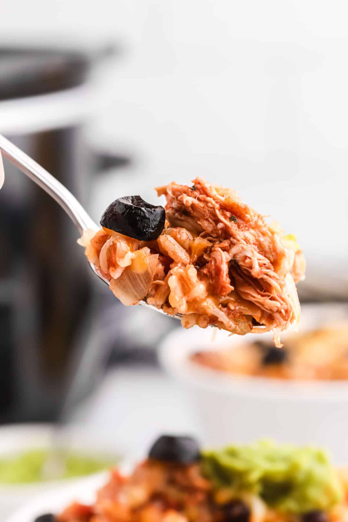 Spoonful of shredded chicken and rice from a slow cooker chicken burrito bowl.