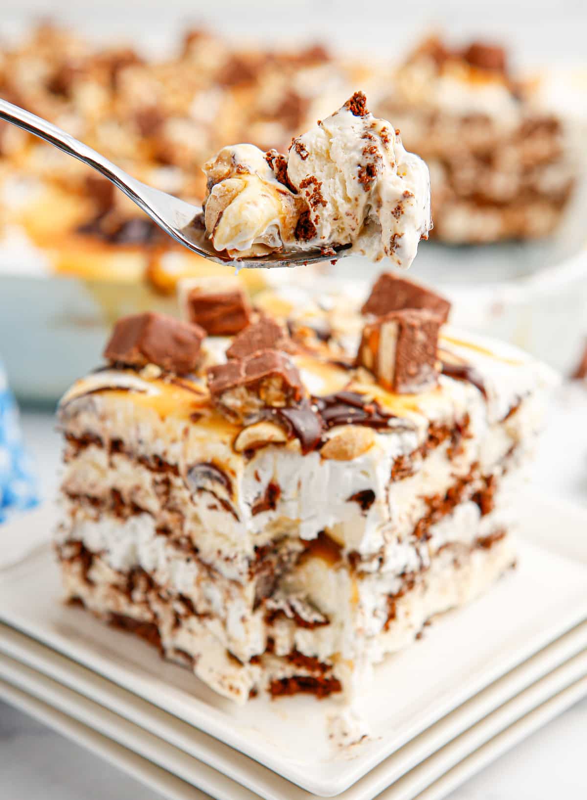 spoonful of snickers ice cream cake lifted from pan Spoonful of frozen snickers ice cream sandwich cake showing layers of whipped topping and crushed candy