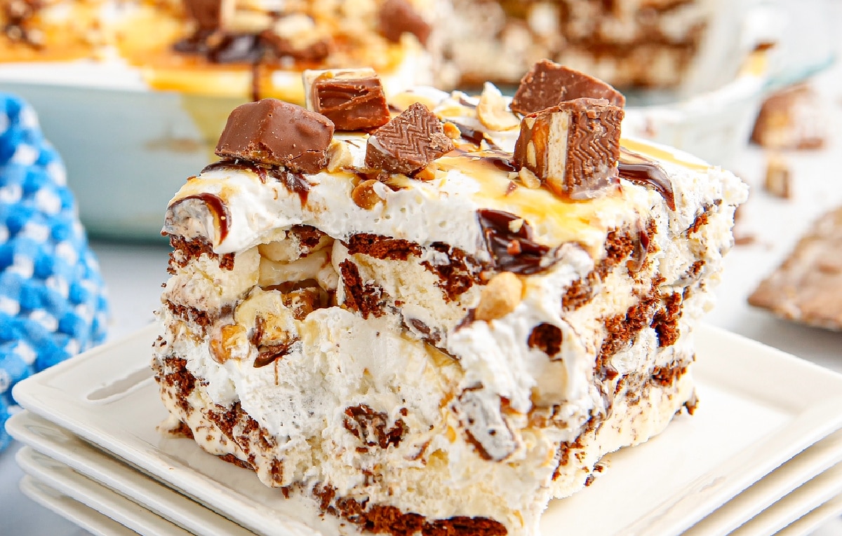 close-up of snickers ice cream sandwich cake slice with layers and toppings Detailed view of frozen snickers ice cream cake slice with whipped topping and caramel drizzle