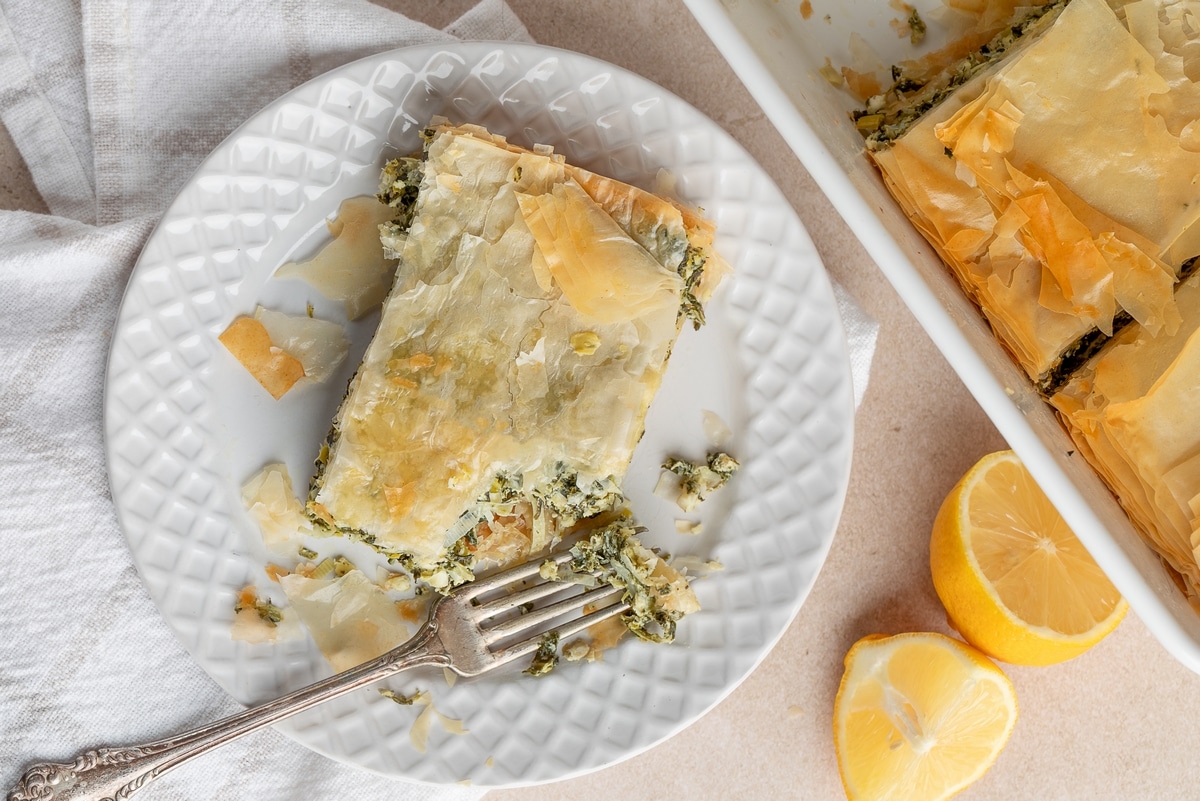 This savory Spanakopita “pie” features a bit of a twist on the traditional filling. Layers of flaky phyllo dough with a rich filling of spinach, artichoke hearts, and sautéed leeks. spanakopita