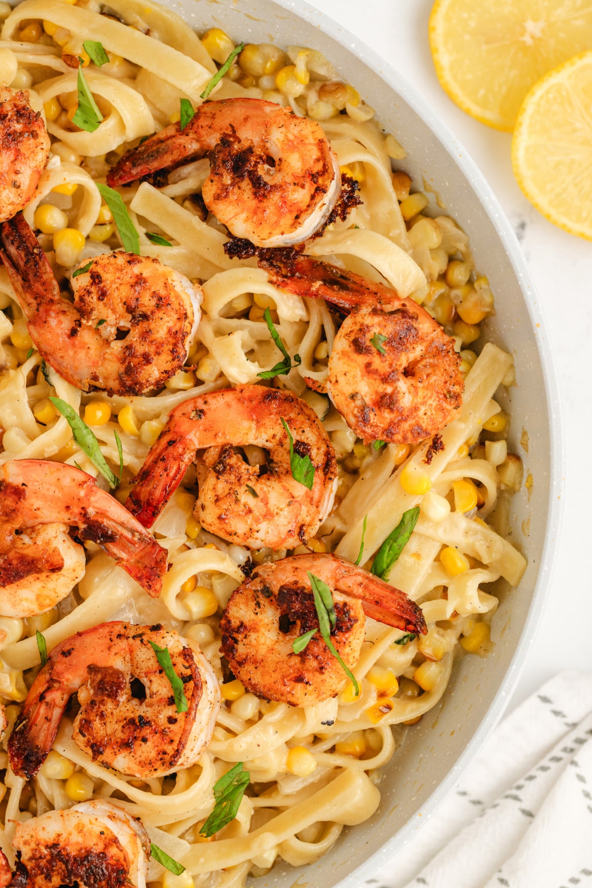 Close-up of blackened shrimp pasta with creamy corn fettuccine in a skillet.