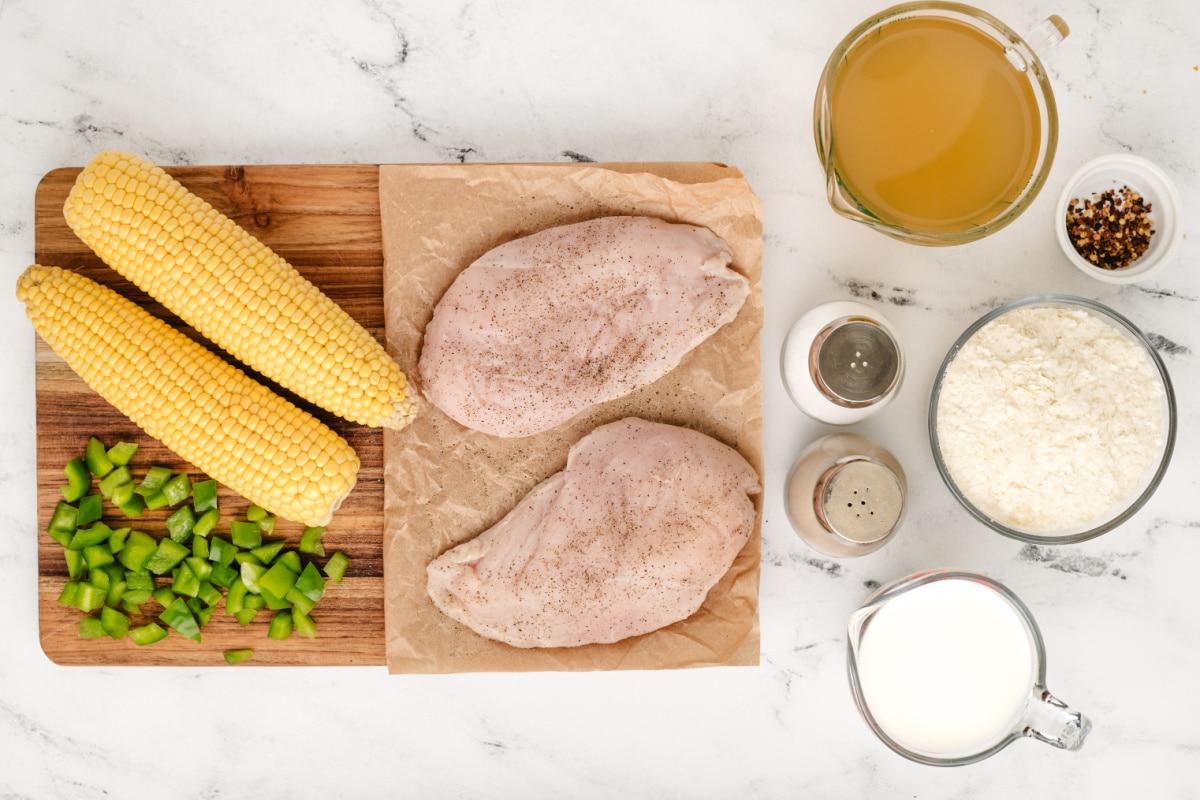 Ingredients for chicken corn chowder including chicken breasts, fresh sweet corn, green bell pepper, chicken broth, whole milk, instant mashed potato flakes, and seasonings.