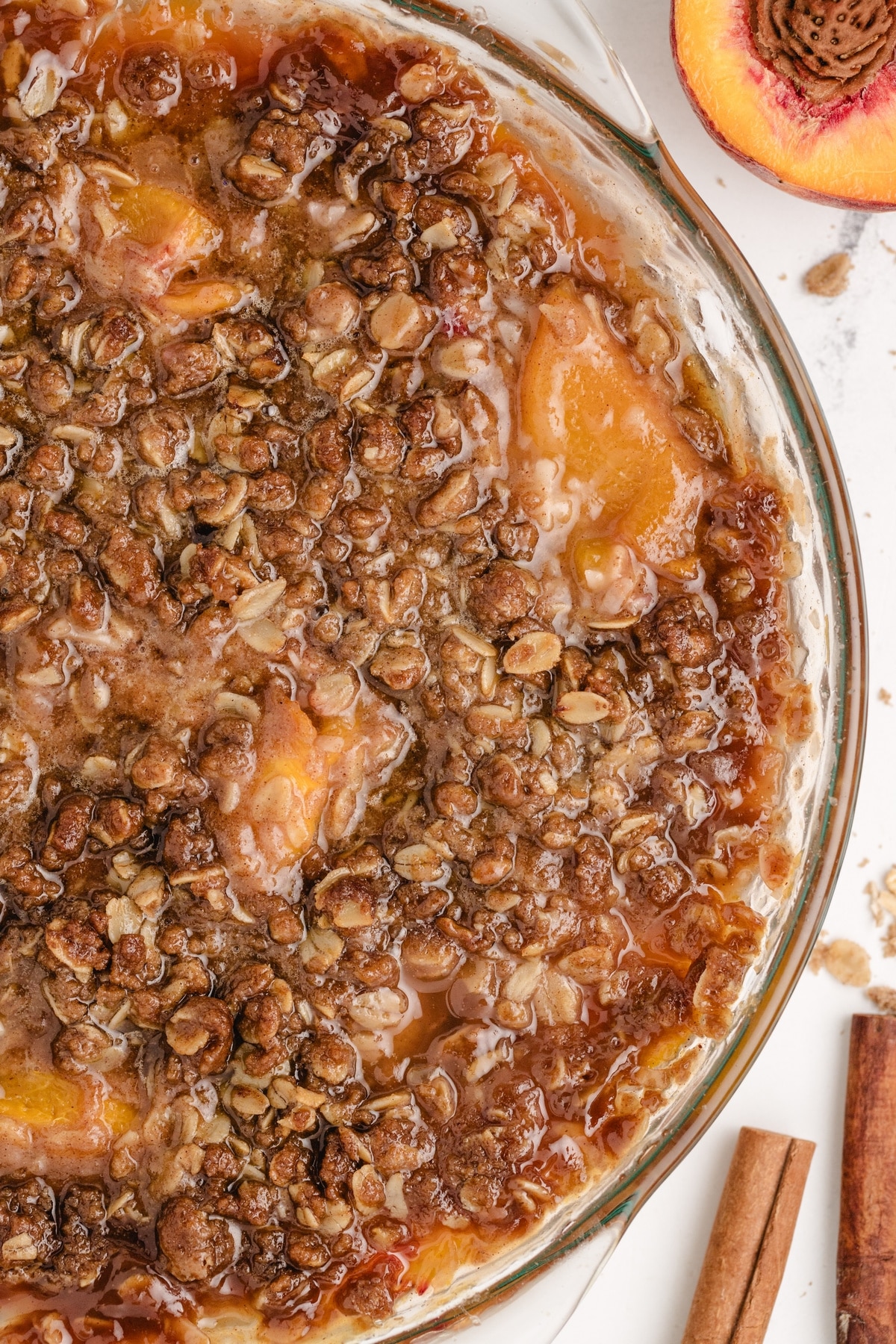 Close-up of golden brown oat topping baked over peaches in a pie dish.