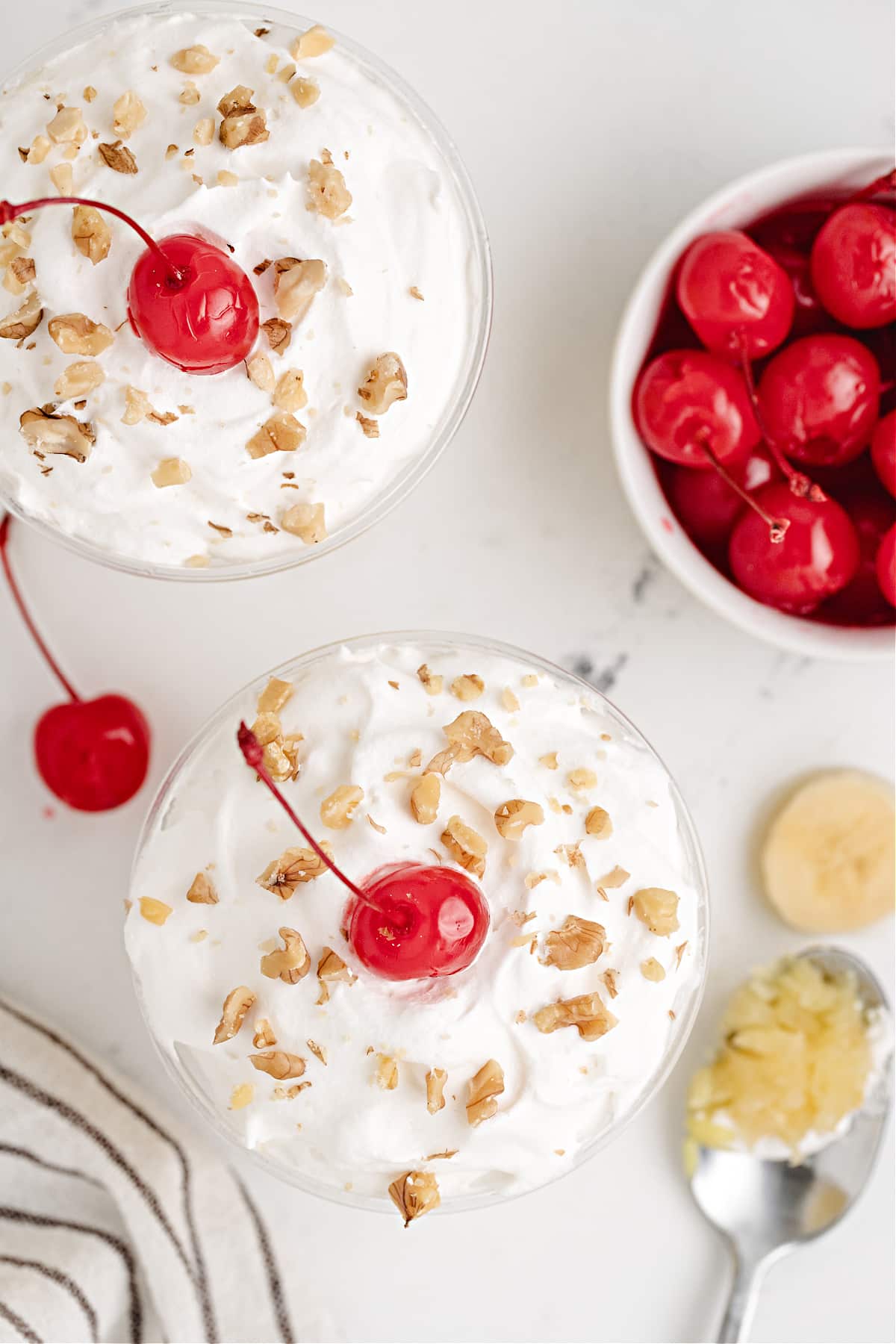 Individual Banana Split Cakes handheld banana split cakes in individual cups with whipped topping, cherries and walnuts a nostalgic 90s dessert