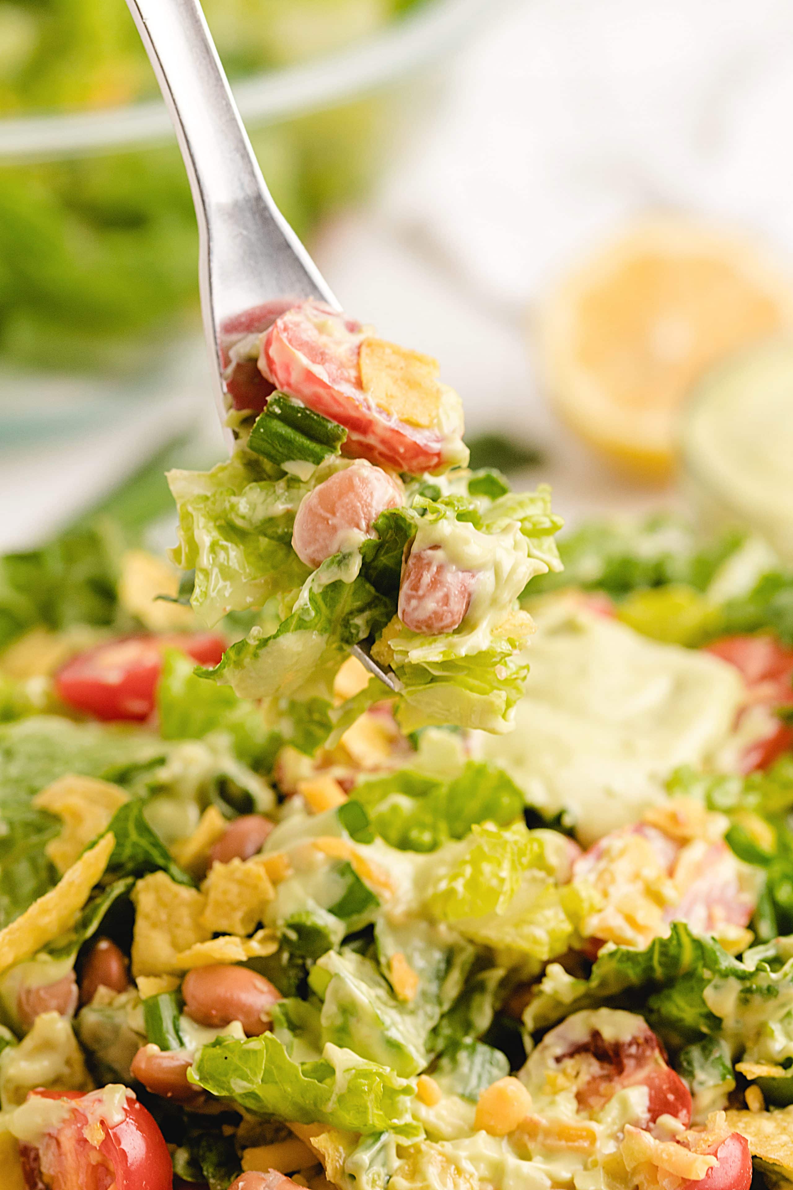 Mexican salad tossed in creamy avocado dressing with beans and chips Overhead of Mexican chopped salad fully tossed in thick avocado dressing with visible toppings