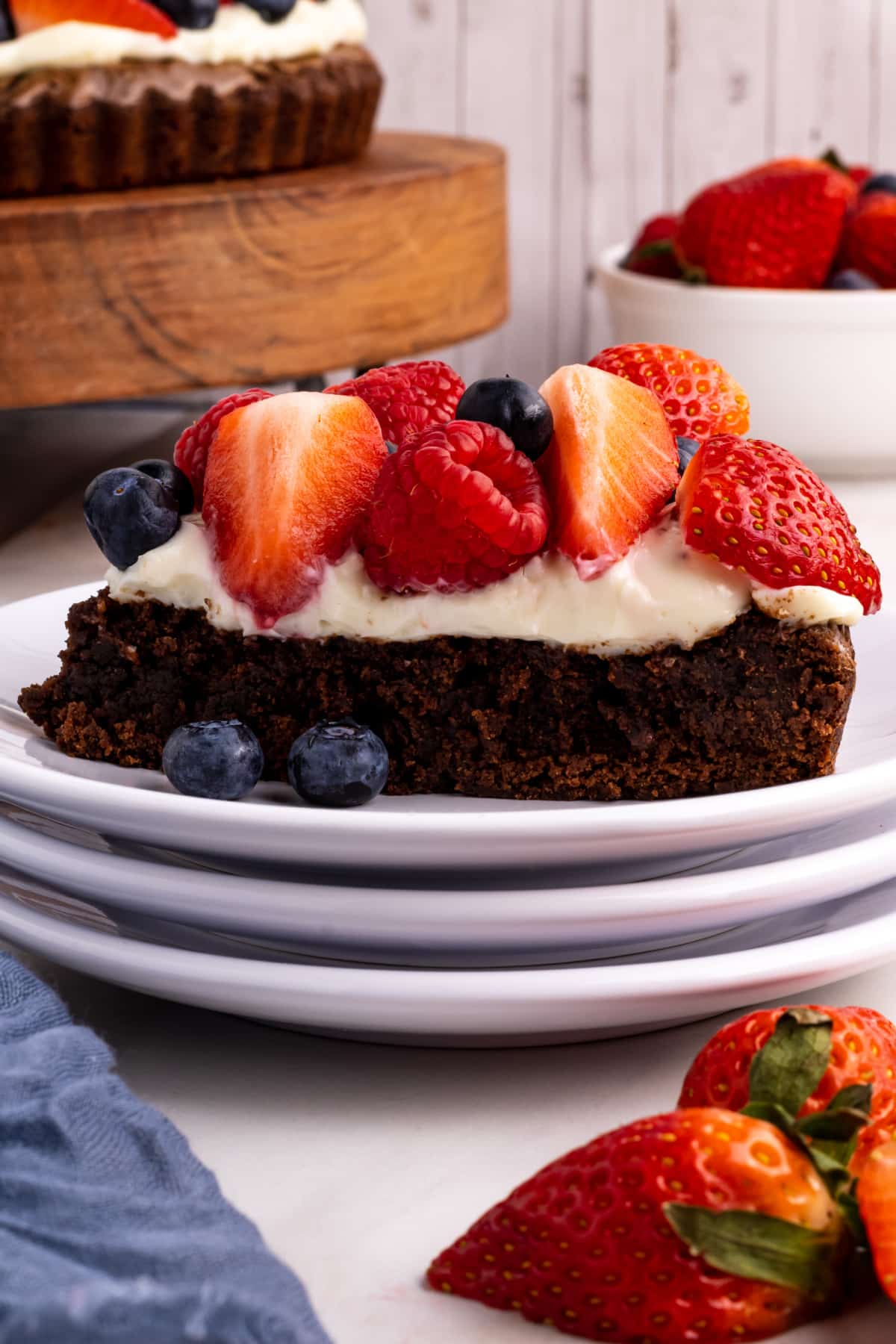Thick slice of brownie fruit pizza on a plate with berries and cream cheese frosting