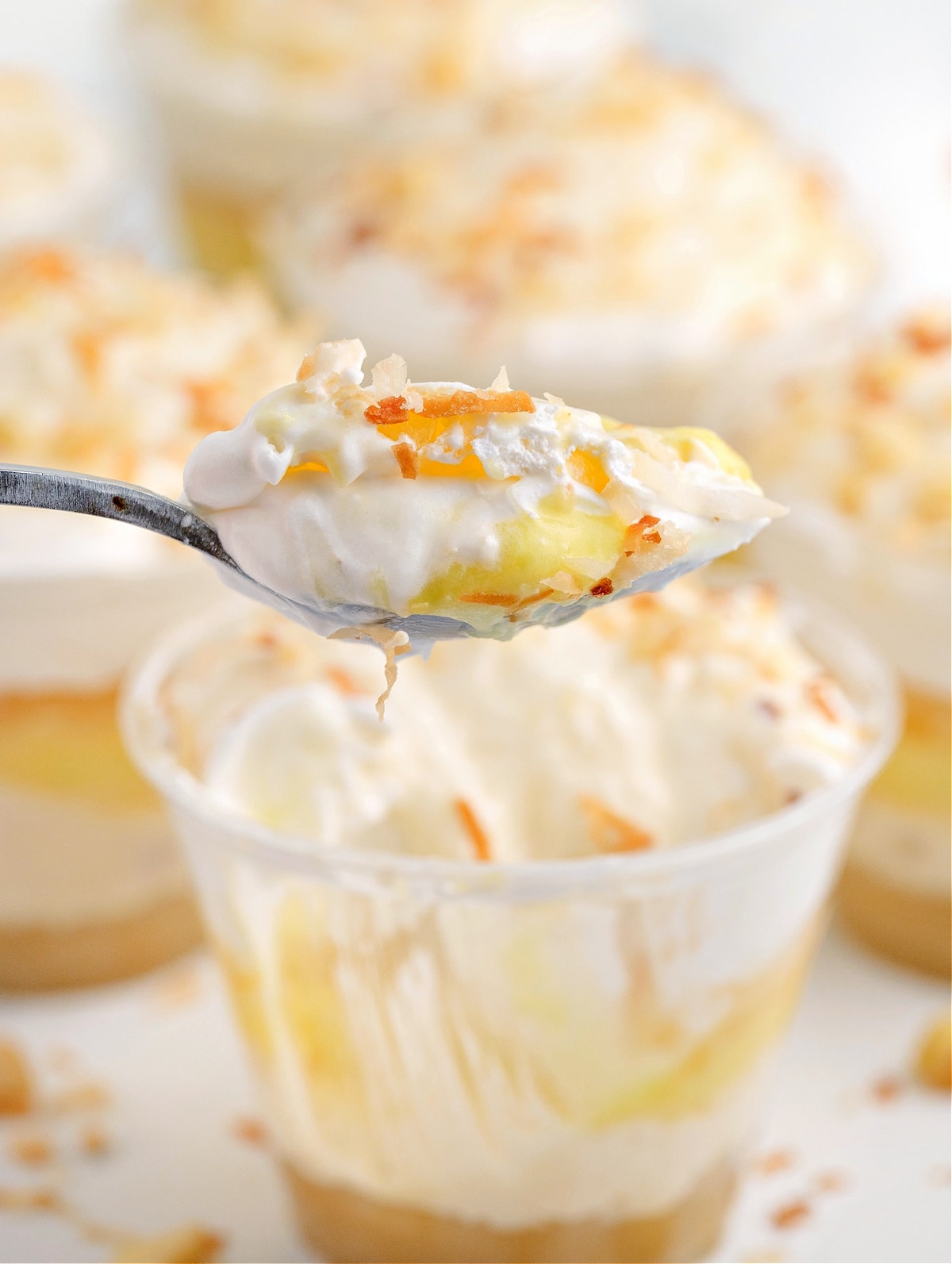 Spoonful of Hawaiian Dream Dessert Cup with creamy pineapple and coconut layers Spoonful of Hawaiian Dream Dessert Cup showing layers of whipped cream, coconut pudding, and pineapple over a macadamia nut crust.