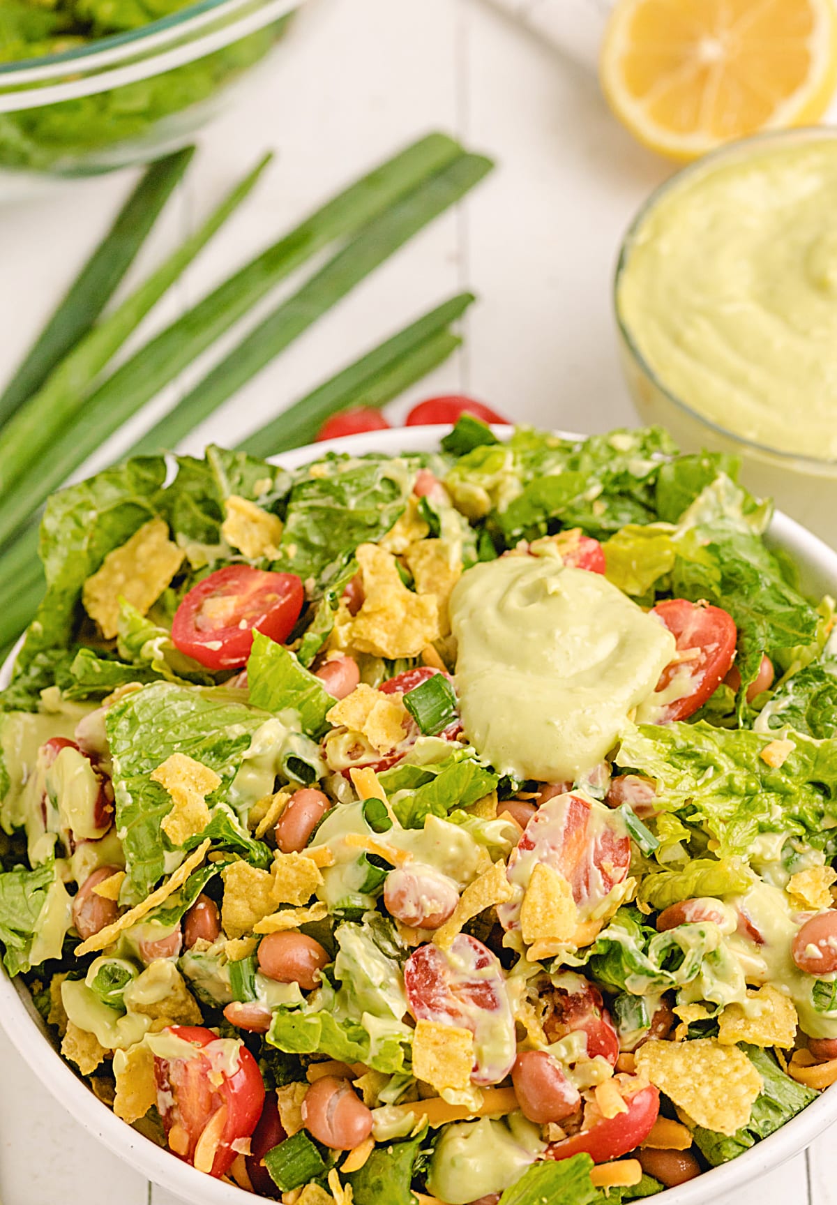 Chopped Mexican salad with avocado dressing in glass bowl Overhead view of chopped Mexican salad with avocado dressing, corn chips, and tomatoes in a bowl