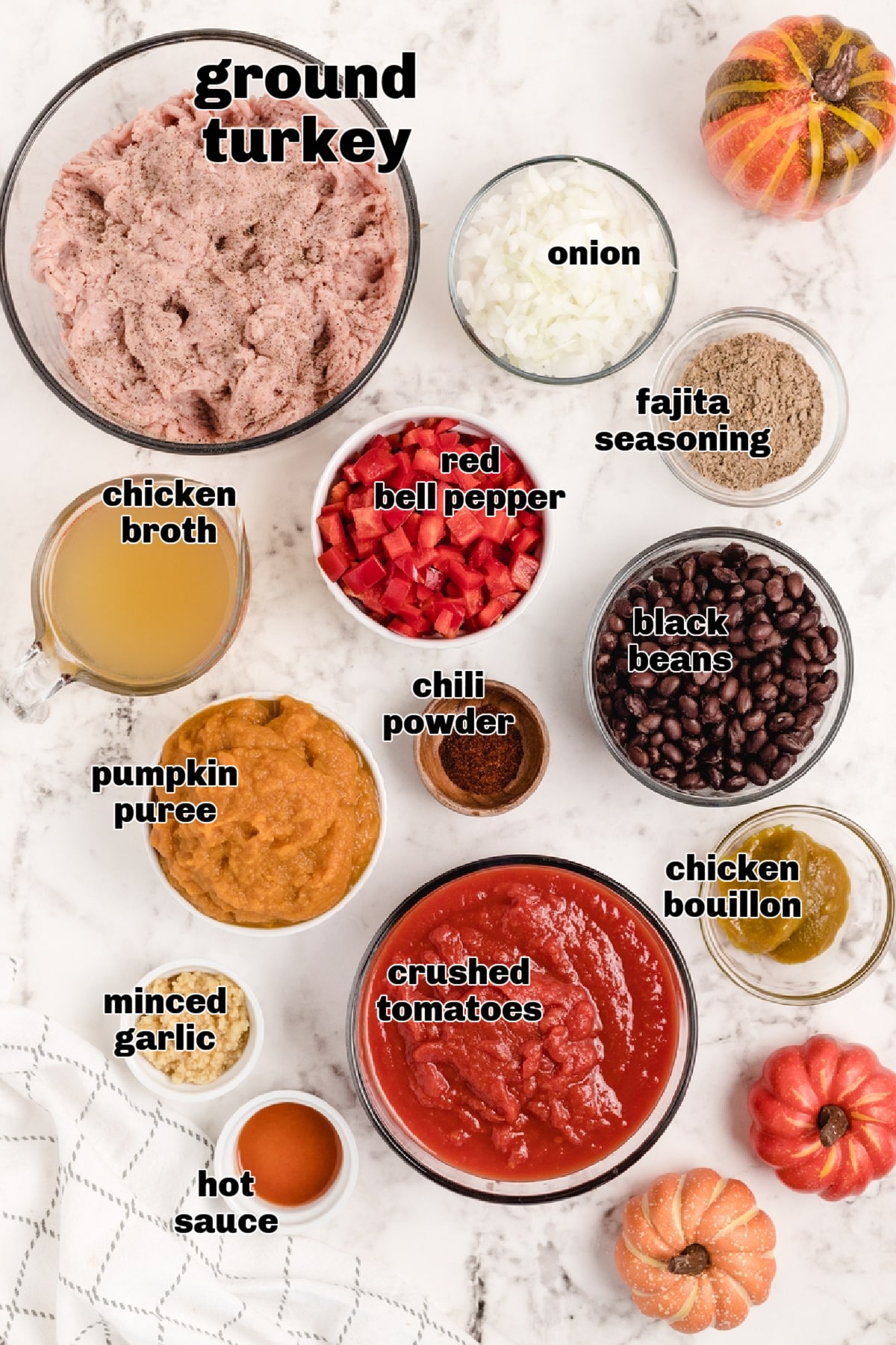 Ingredients for pumpkin chili with ground turkey arranged on a marble surface.