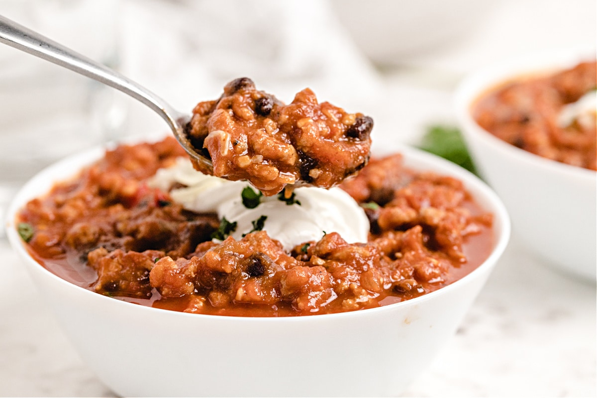 Spoonful of thick pumpkin chili showing beans, turkey, and sauce.