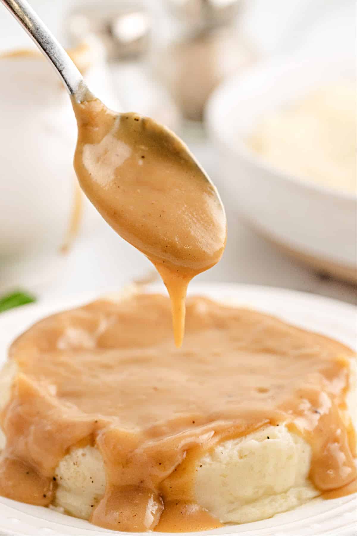 Turkey Gravy from Wings on Mashed Potatoes Spoonful of turkey gravy from wings over mashed potatoes, showing the smooth texture of this easy make ahead gravy recipe. Perfect for Thanksgiving or Sunday dinner.