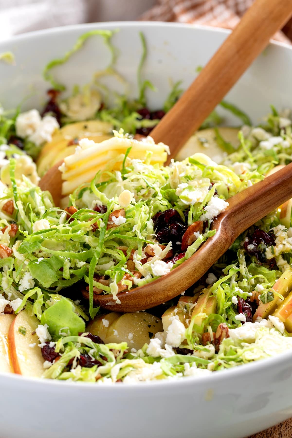 Shaved Brussels Sprouts Salad being served. Salad in a white bowl with a serving ready to go