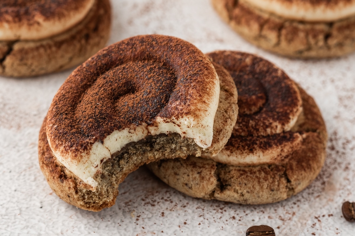 Cocoa-dusted tiramisu cookie with a bite. Frosted tiramisu cookie dusted with cocoa powder and a bite taken, highlighting the fluffy mascarpone topping.