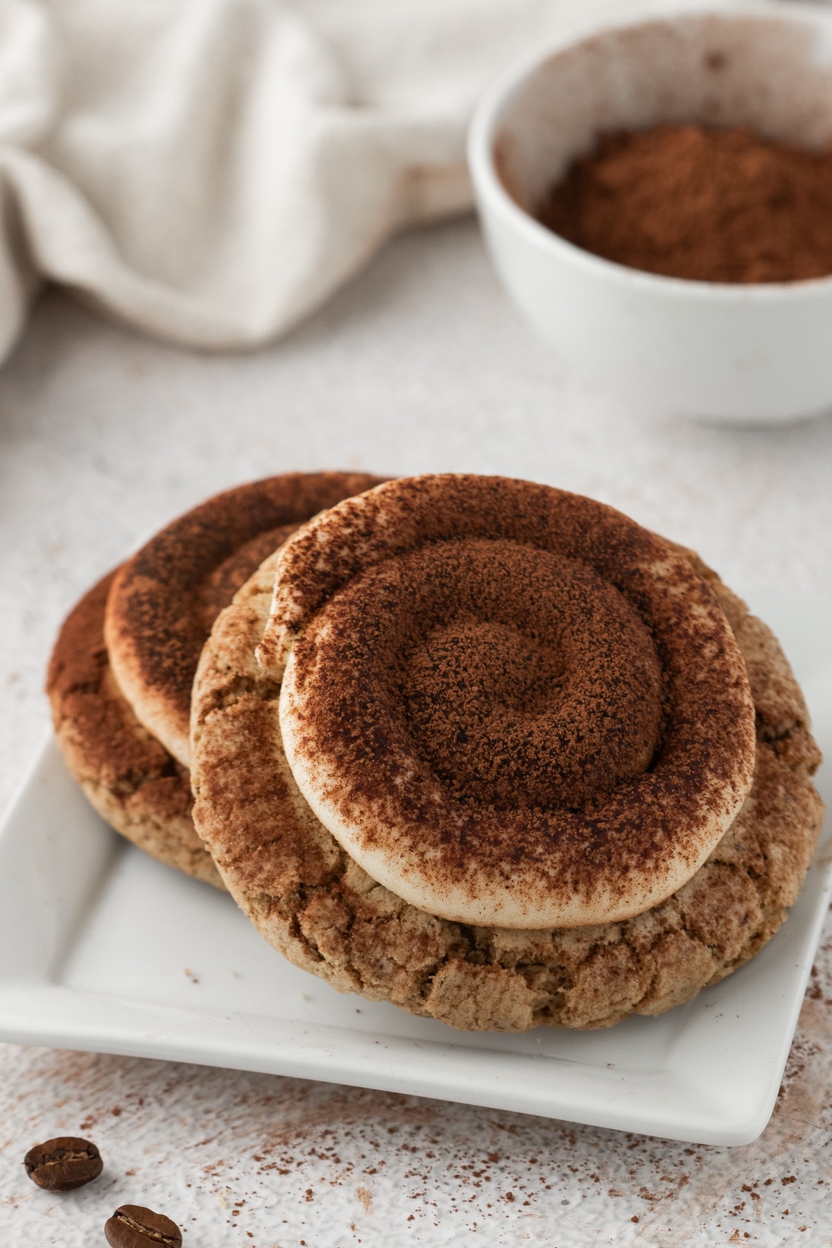Espresso cookies with mascarpone. Multiple tiramisu cookies arranged on a baking sheet, decorated with creamy frosting and cocoa powder.