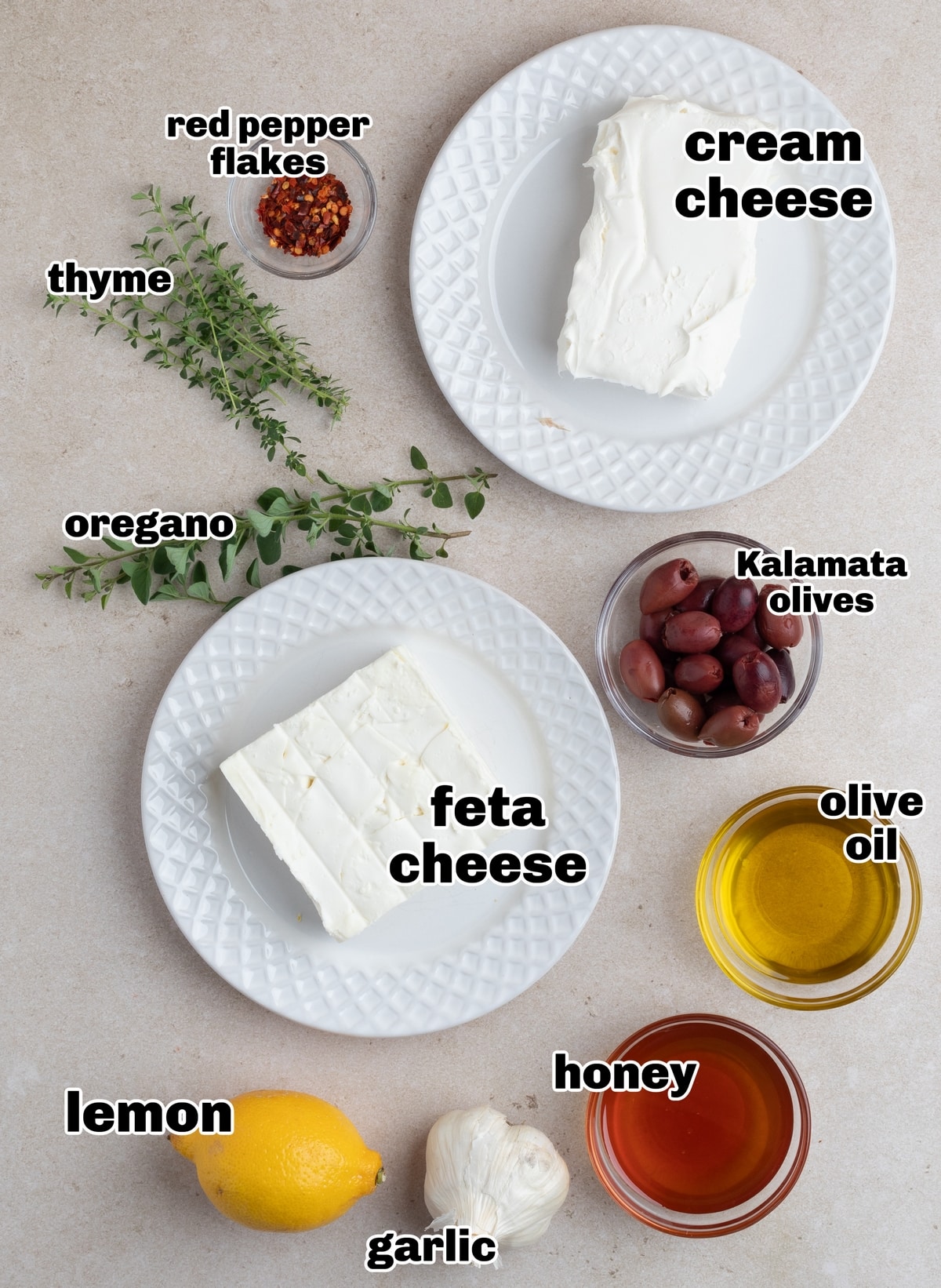 Ingredients for whipped feta roasted garlic dip with honey including feta, cream cheese, roasted garlic, lemon, and honey.