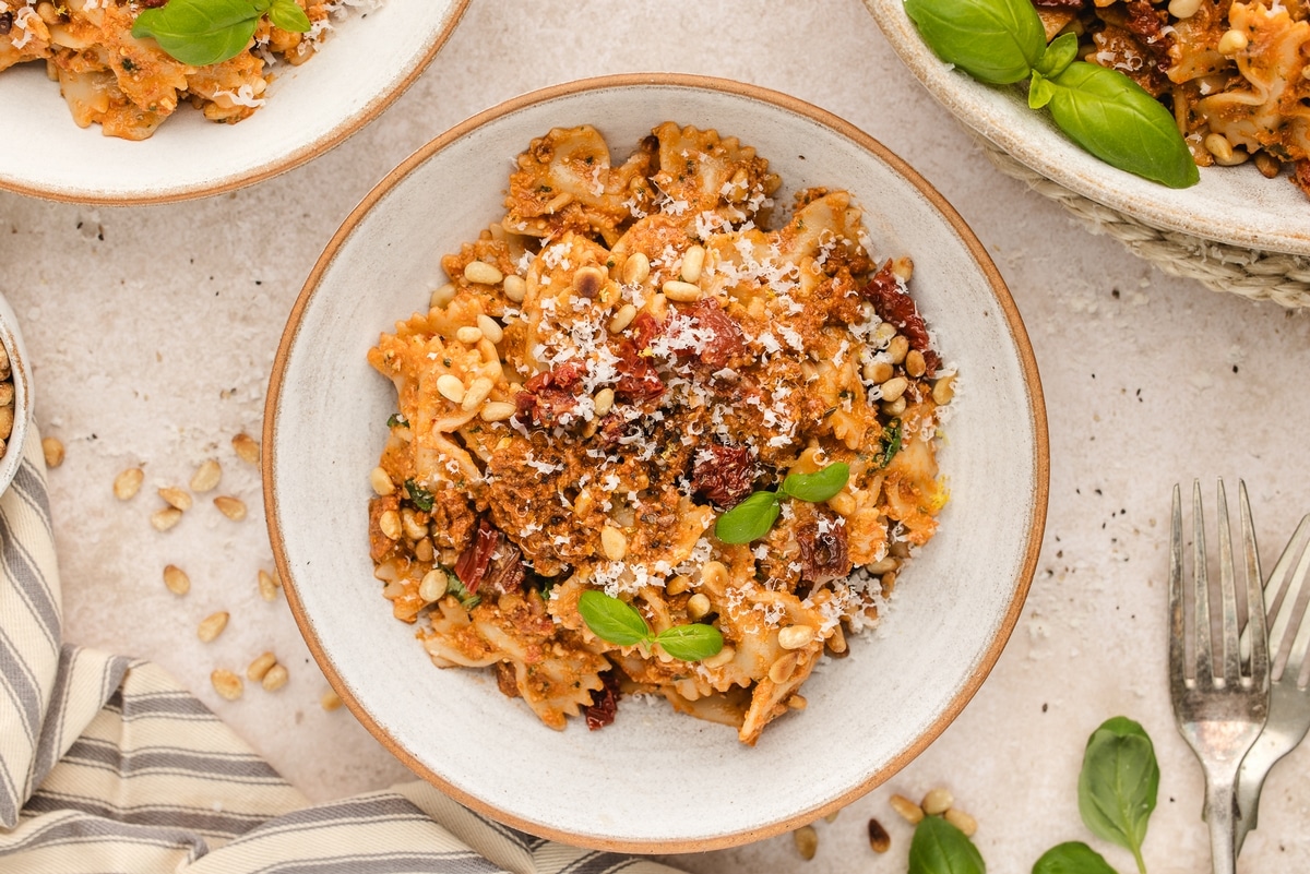 Sun-Dried Tomato Pesto Pasta on a tabletop three plates of Sun-Dried Tomato Pesto Pasta