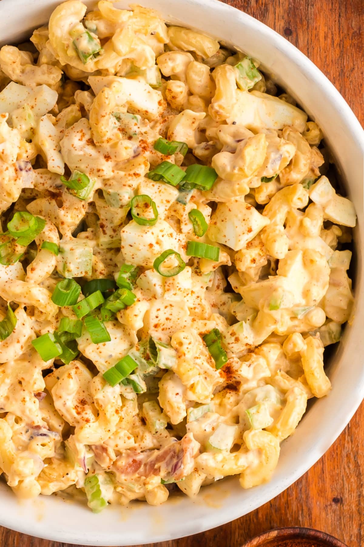 Deviled Egg Pasta Salad top view A top-down view of deviled egg pasta salad in a large bowl, showing creamy pasta, bacon, and green onions.