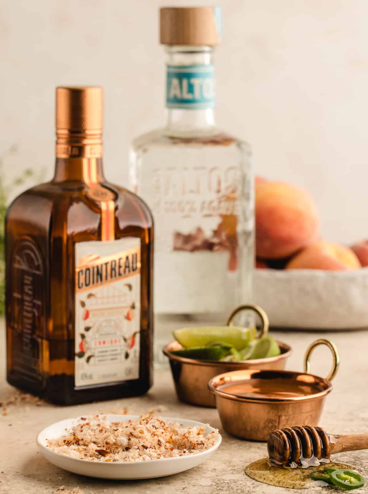 Ingredient shot featuring tequila, hot honey, lime juice, peach purée, and chili salt arranged on a surface.