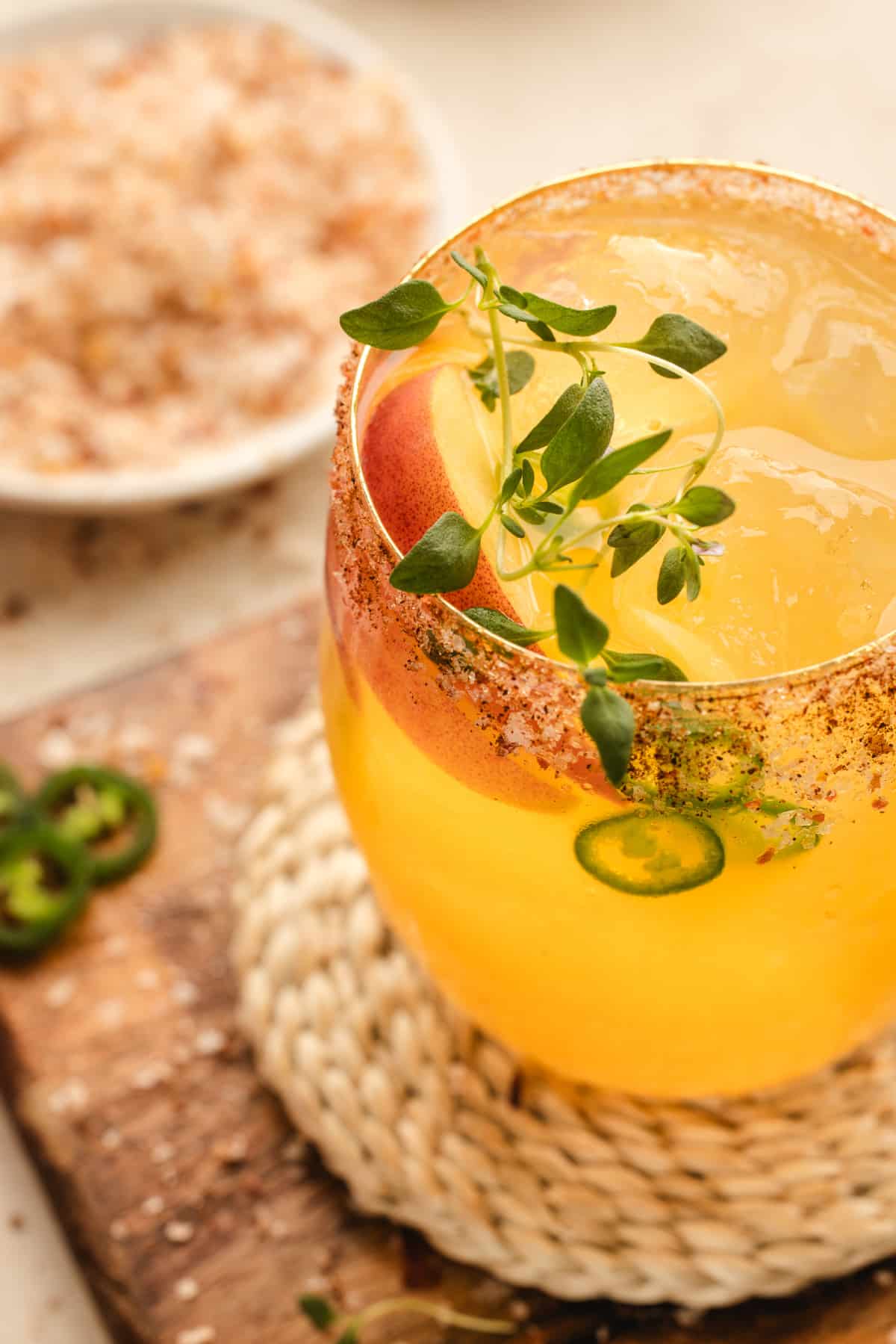 A glass being filled with the margarita as the cocktail is poured over ice, with garnishes nearby.