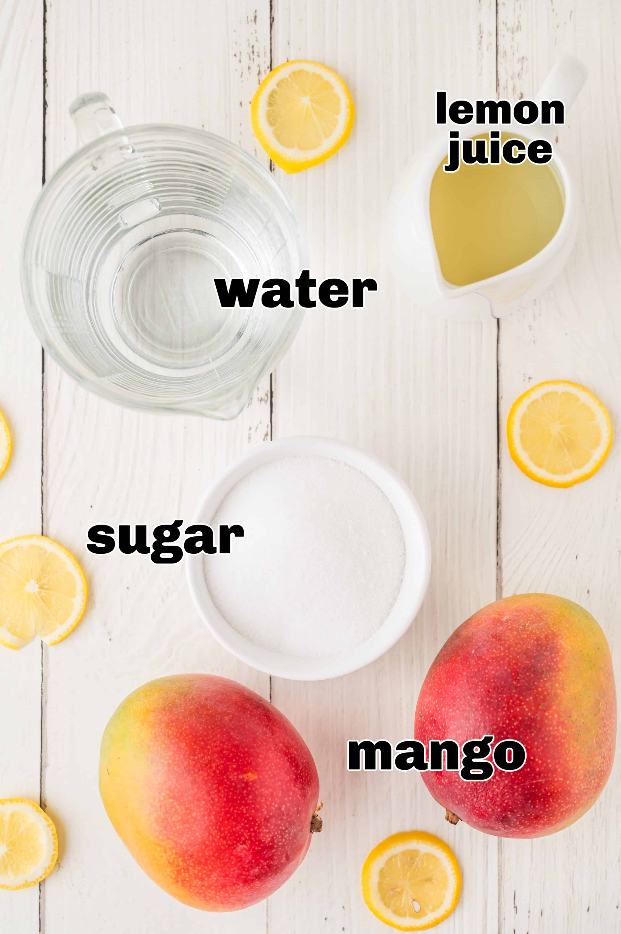 A flat lay of fresh mango, lemons, sugar, and water arranged on a countertop, ready to make the homemade lemonade.