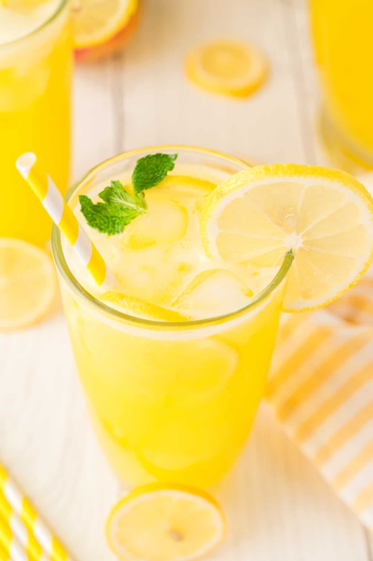 A single glass of mango lemonade with ice, fresh mint, and a lemon slice on the rim, ready to drink.