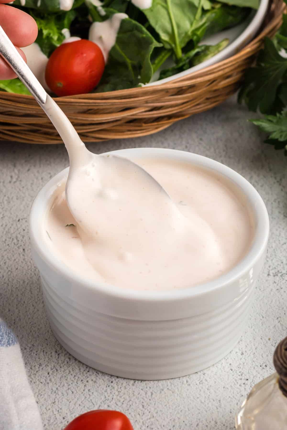 Stirring Creamy Mayonnaise Salad Dressing Creamy mayonnaise salad dressing being stirred in a white ramekin with a spoon