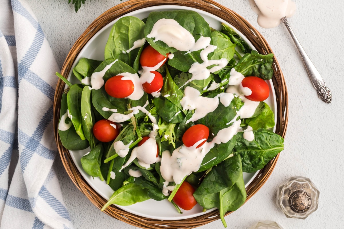 Creamy Mayonnaise Salad Dressing on a spinach salad Creamy salad dressing drizzled over fresh spinach leaves