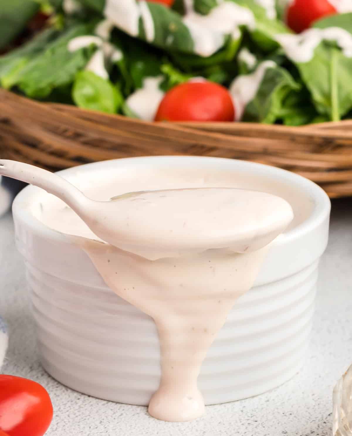 Creamy Mayonnaise Salad Dressing spilling out of a ramekin Spoon lifting out creamy salad dressing with some spilling over the side of the ramekin