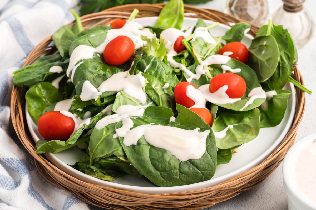 Creamy Mayonnaise Salad Dressing on greens with tomato Fresh spinach greens topped with creamy mayonnaise salad dressing