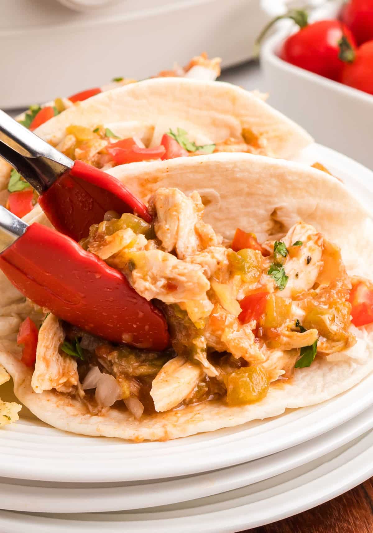 Flat lay of several shredded taco chicken tacos arranged on a platter.