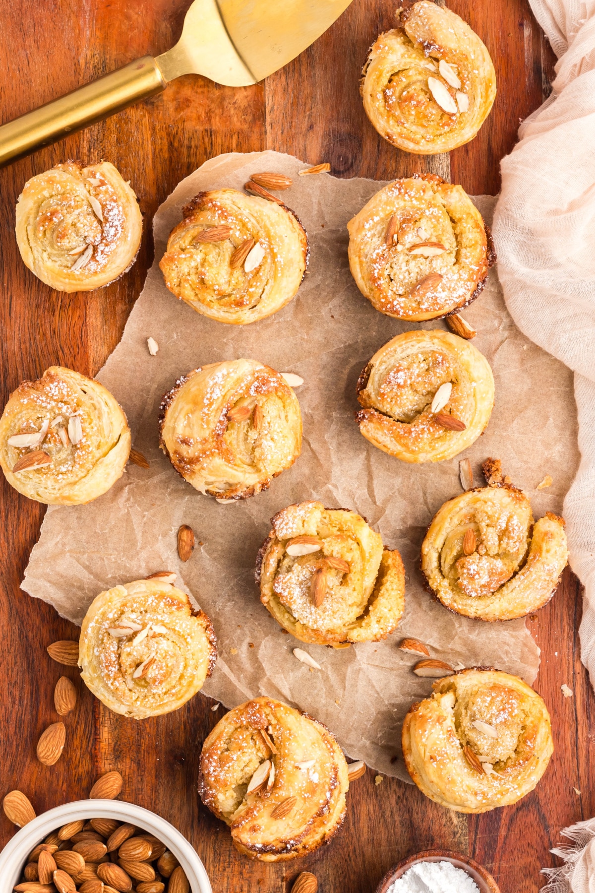 almond cruffin batch Overhead shot of several freshly baked cruffins in a muffin pan, each with a golden, spiral top.