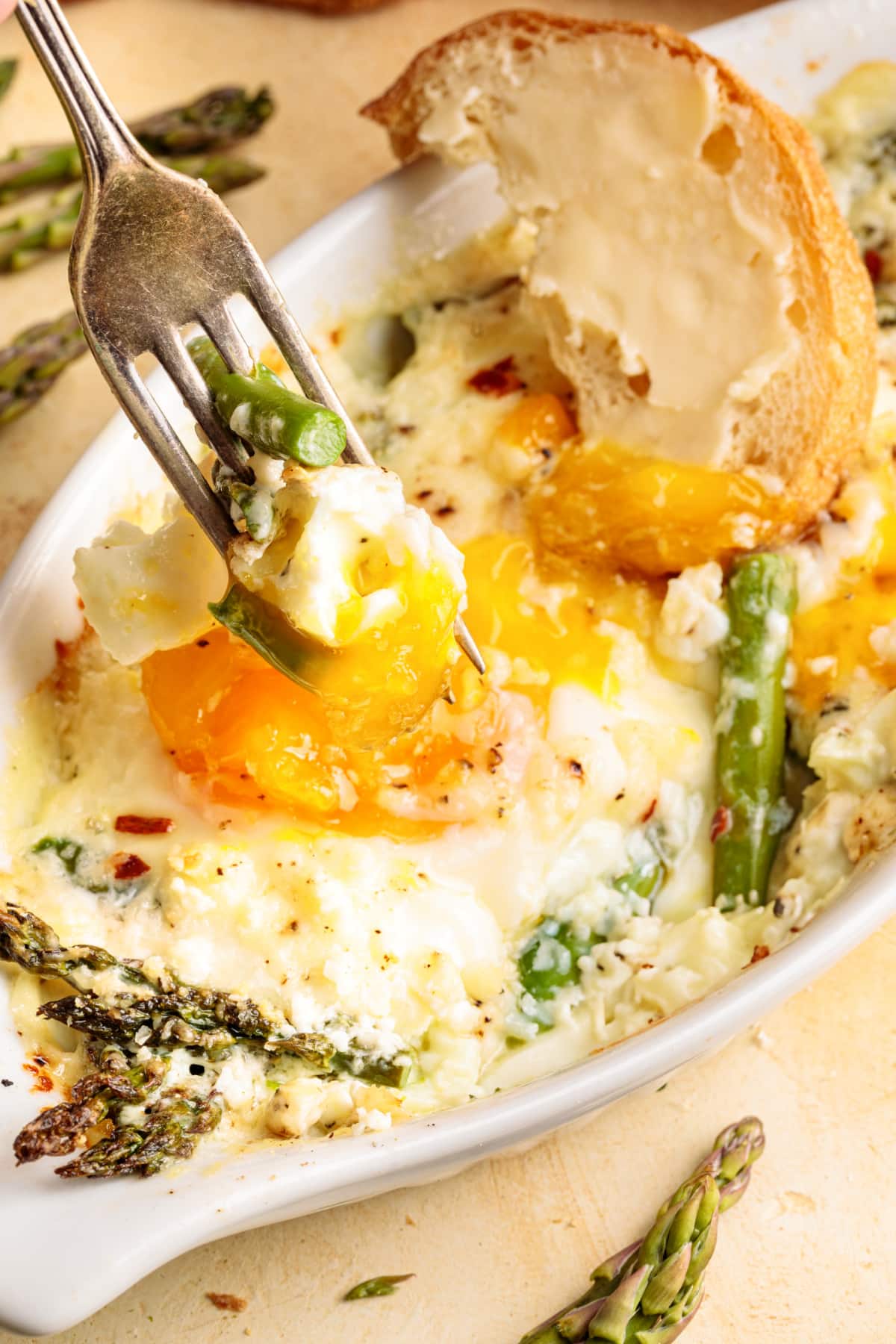 Fork lifting a bite of baked eggs out of the dish, showing the creamy texture.