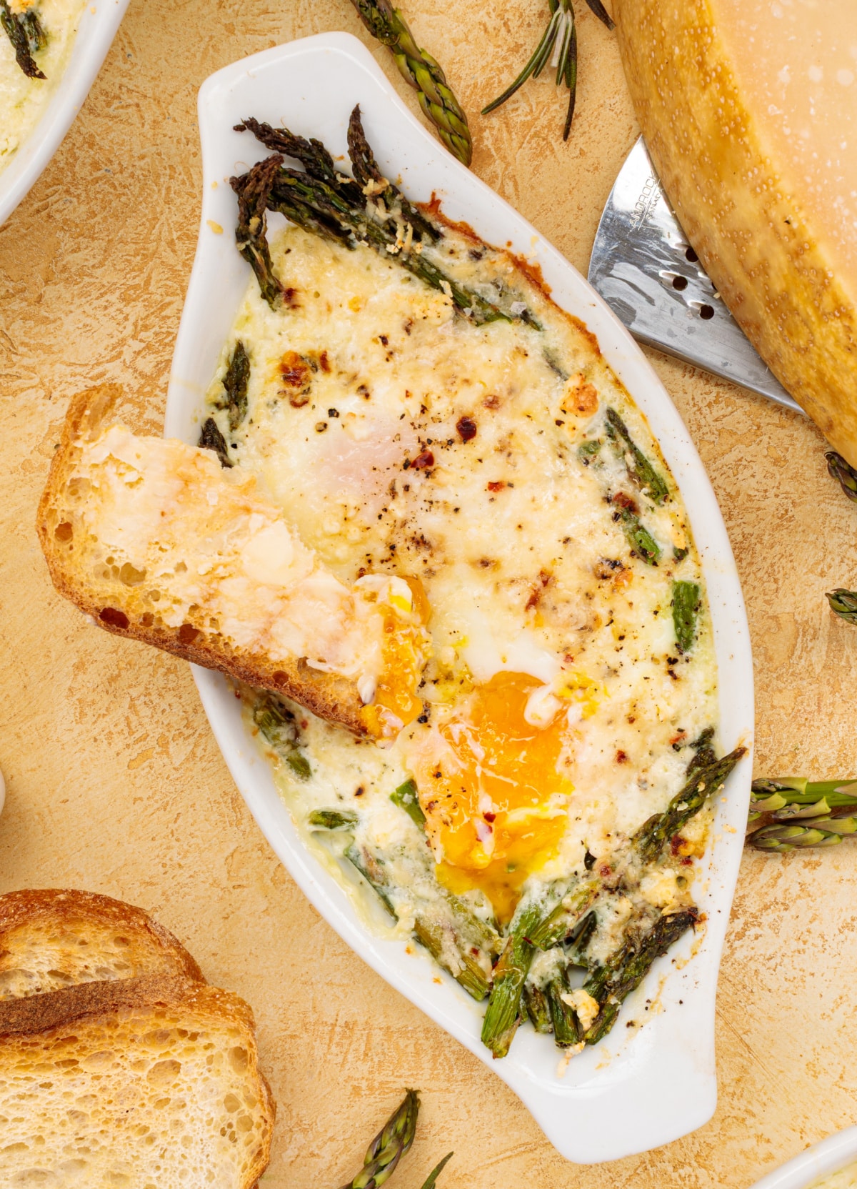 Top view of baked eggs served with a golden, buttery toast dipper alongside the dish.