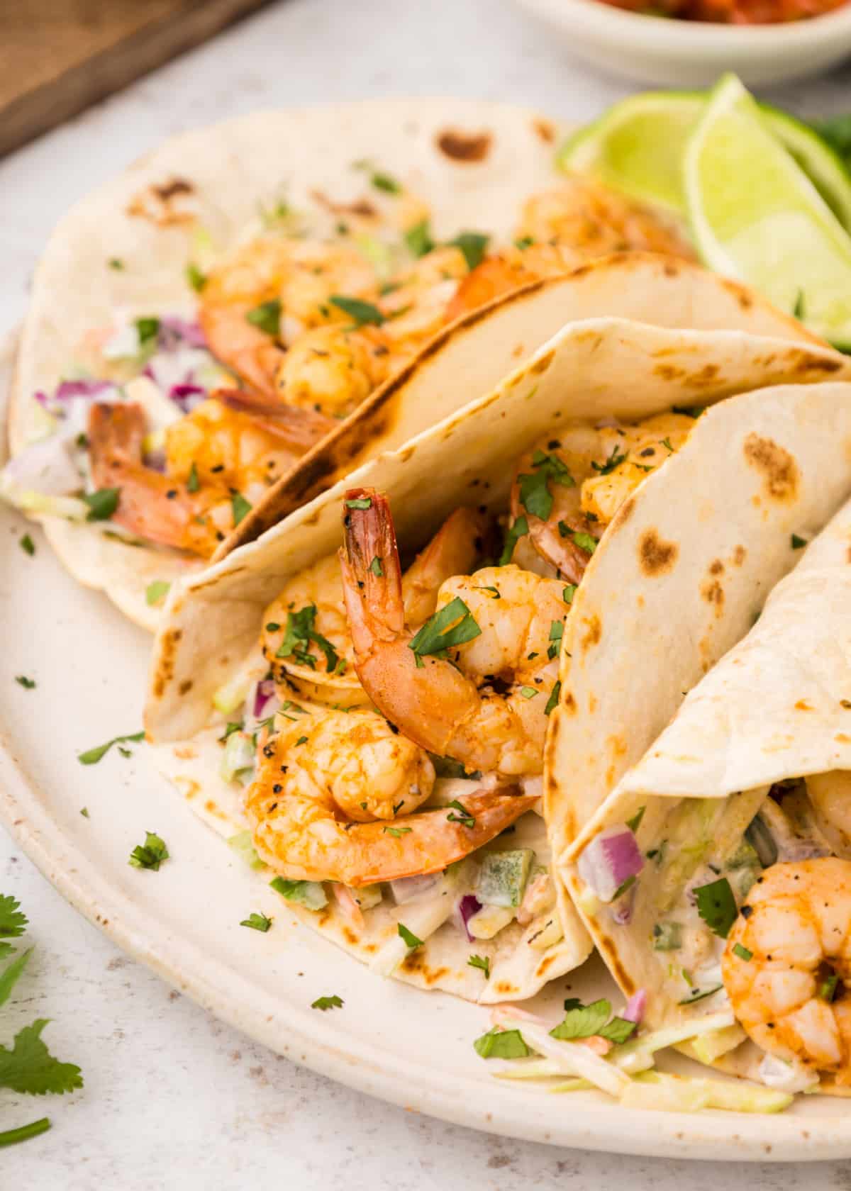 a trio of Cajun Shrimp Tacos Side view of three tacos showing shrimp and creamy slaw tucked into soft tortillas