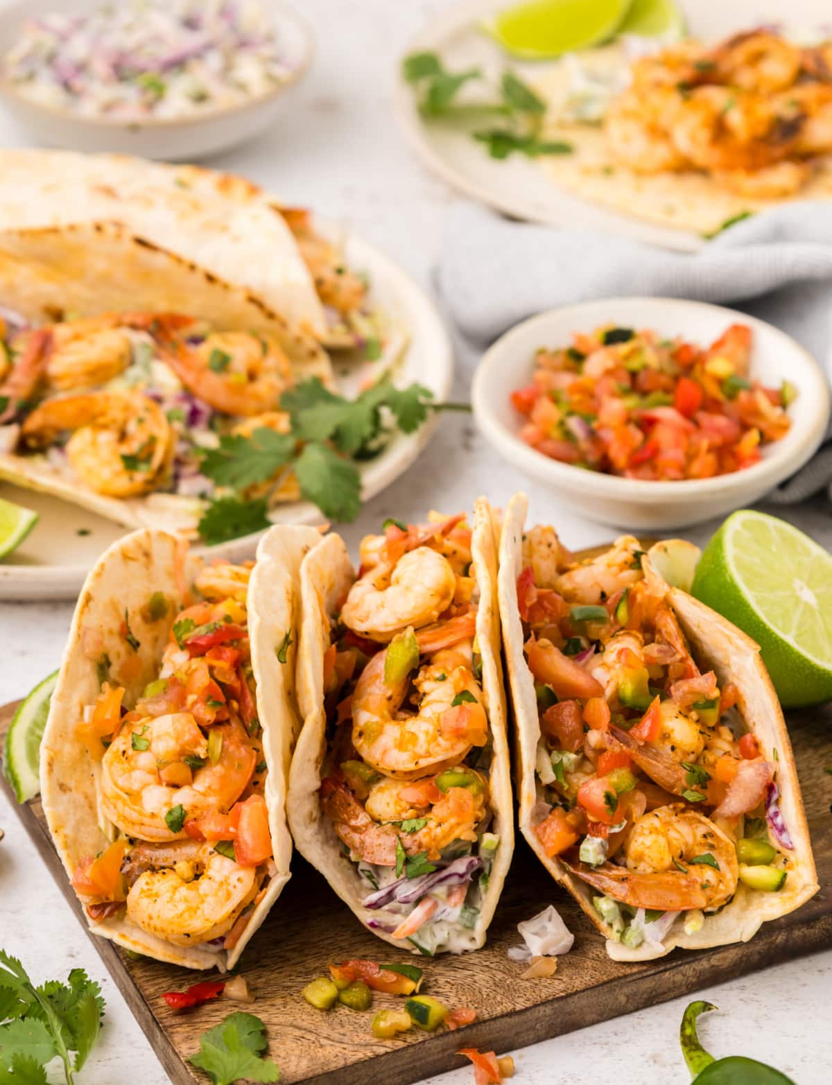 Cajun Shrimp Tacos with lime Three Cajun shrimp tacos on a cutting board with lime wedges on the side