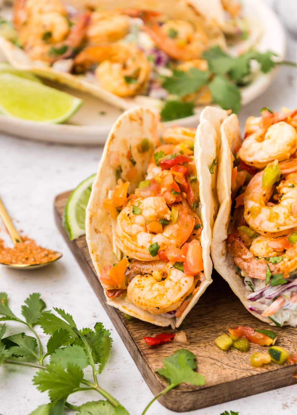 Cajun Shrimp Tacos on a cutting board Two filled Cajun shrimp tacos on a wooden cutting board, showing shrimp and slaw inside