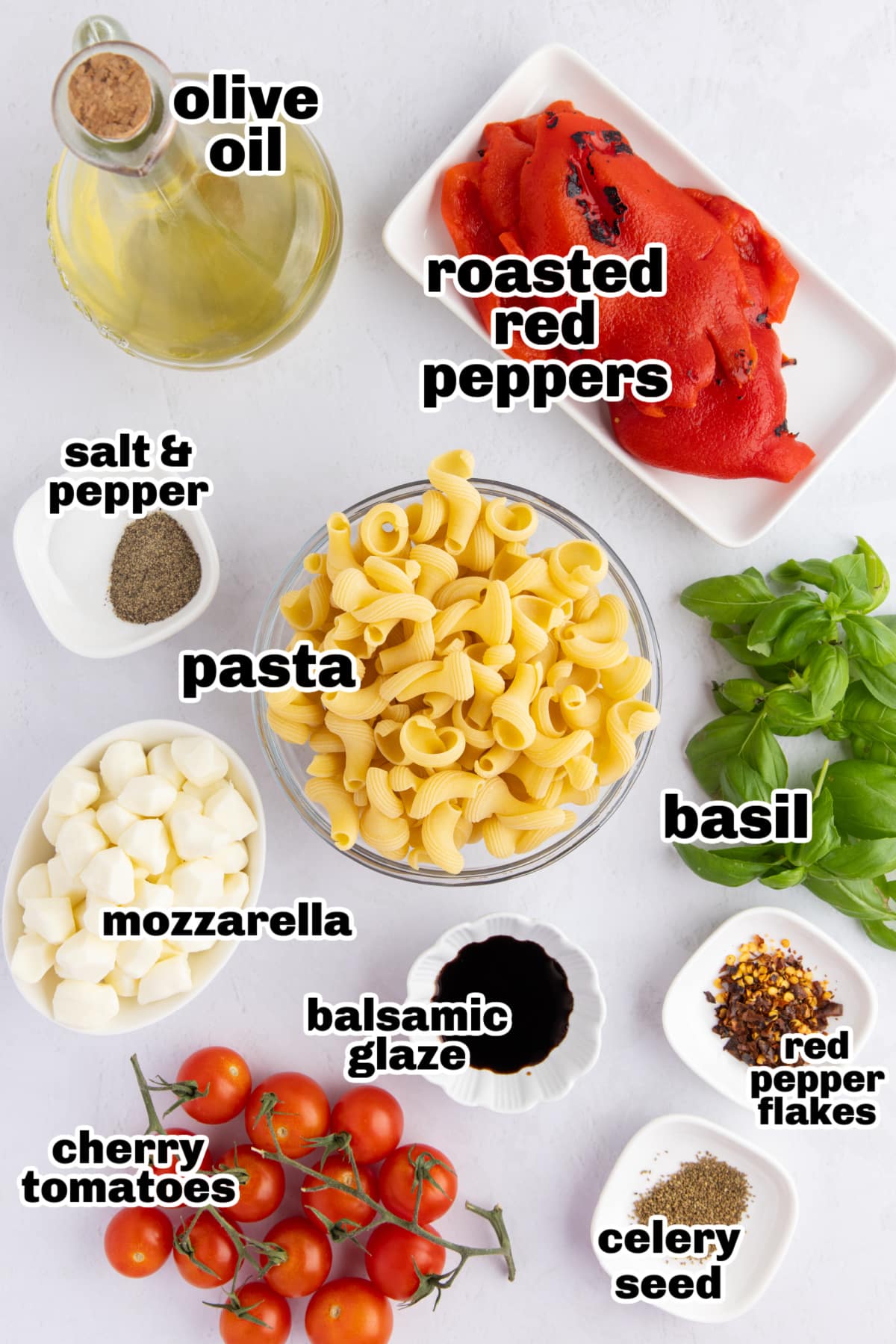 Caprese Pasta Salad with Roasted Red Peppers ingredients Flat lay of the ingredients for caprese pasta salad with roasted red peppers, including pasta, mozzarella pearls, tomatoes, basil, and balsamic glaze.