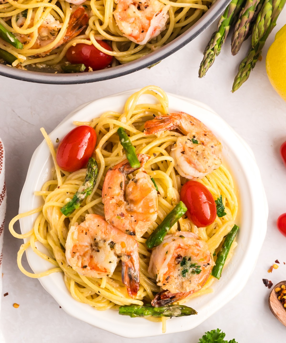 a plate of Garlic Shrimp Pasta with Asparagus and Tomatoes Serving of garlic shrimp pasta in a white bowl, with shrimp, asparagus, and tomatoes clearly visible.