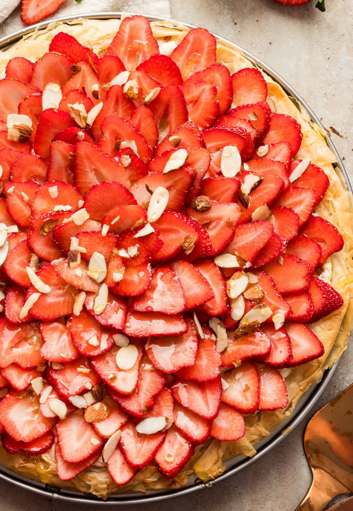 Overhead view of a fully assembled strawberry goat cheese tart with phyllo dough on a pizza pan.